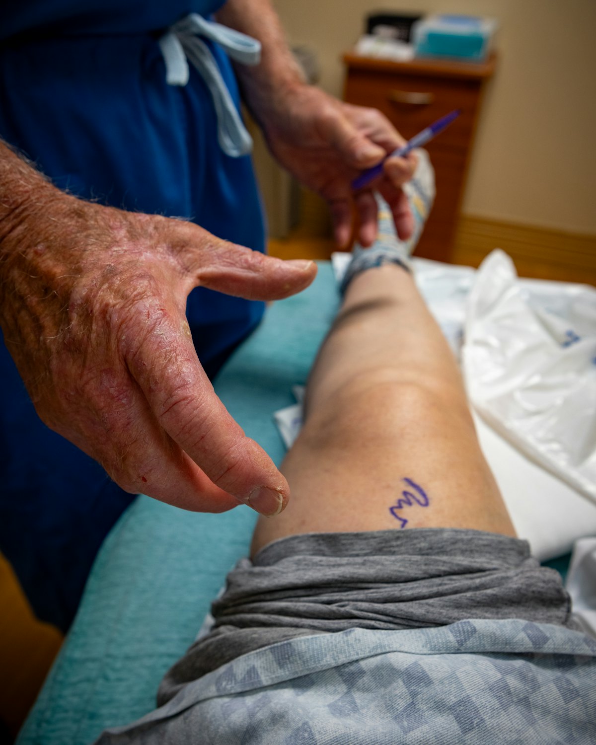 Mãos de um médico examinando o joelho de um paciente